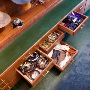 Eine Ansicht von Schubladen bei Aventures de Paulette in Hamburg, gefüllt mit einer Vielfalt an Fliegen, Krawatten, Gürteln, Ketten und Handschuhen, entdecke stilvolle Accessoires für deinen Look