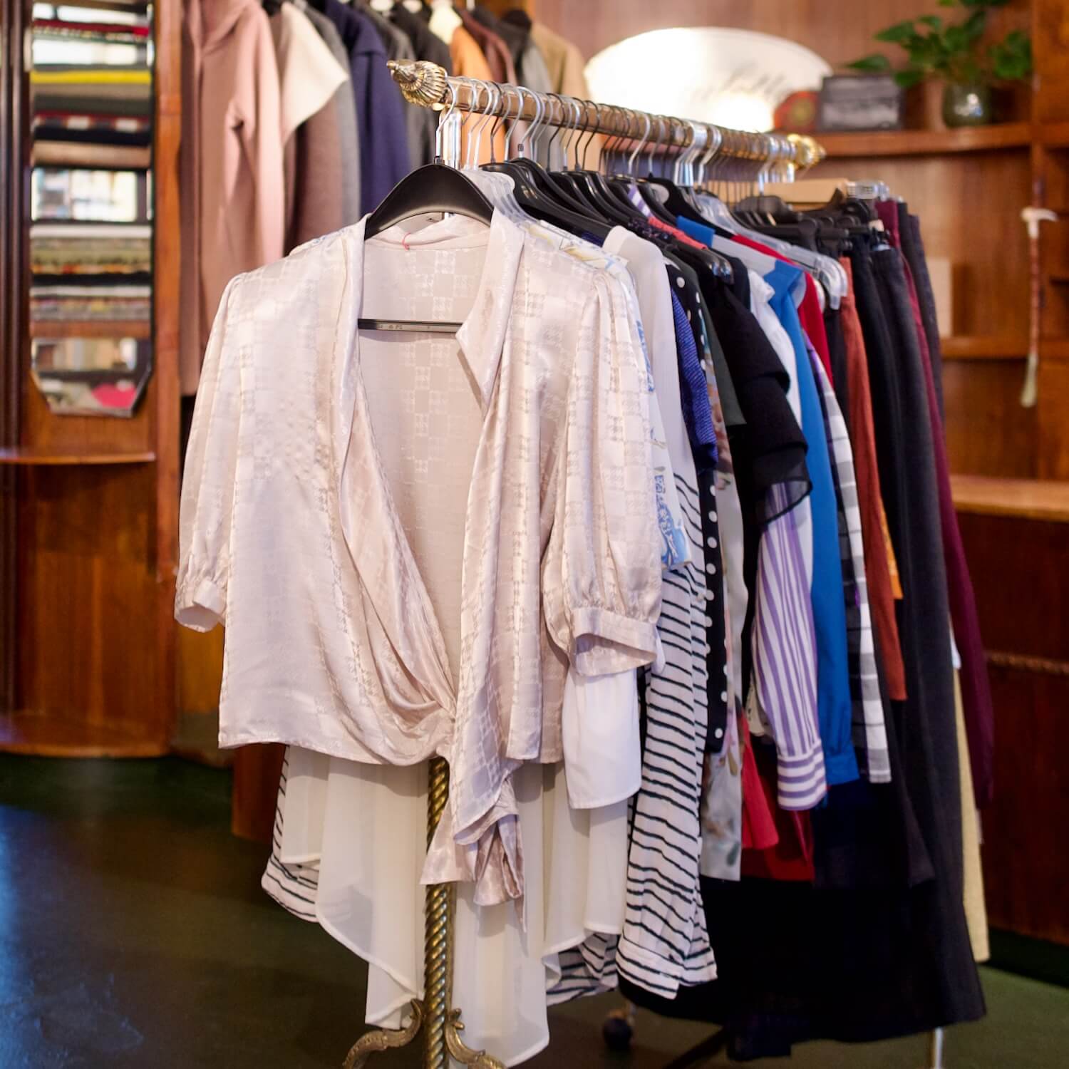 Ein Kleiderstand mit einer Vielzahl von Secondhand-Kleidungsstücken, darunter Blusen, Röcke und vieles mehr, bei Aventures de Paulette in Hamburg, entdecke nachhaltige Mode.