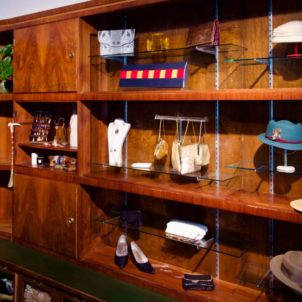 Vielfältige Auswahl an Vintage-Schmuck, Handtaschen und Hüten bei Aventures de Paulette in Hamburg, ansprechend präsentiert im Innenraum des Ladens.